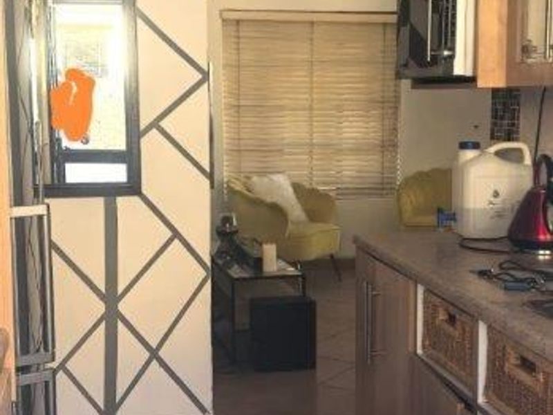 A compact kitchen featuring built-in cabinetry and tiled flooring, showing signs of wear and requiring cosmetic updates to improve the overall aesthetic.