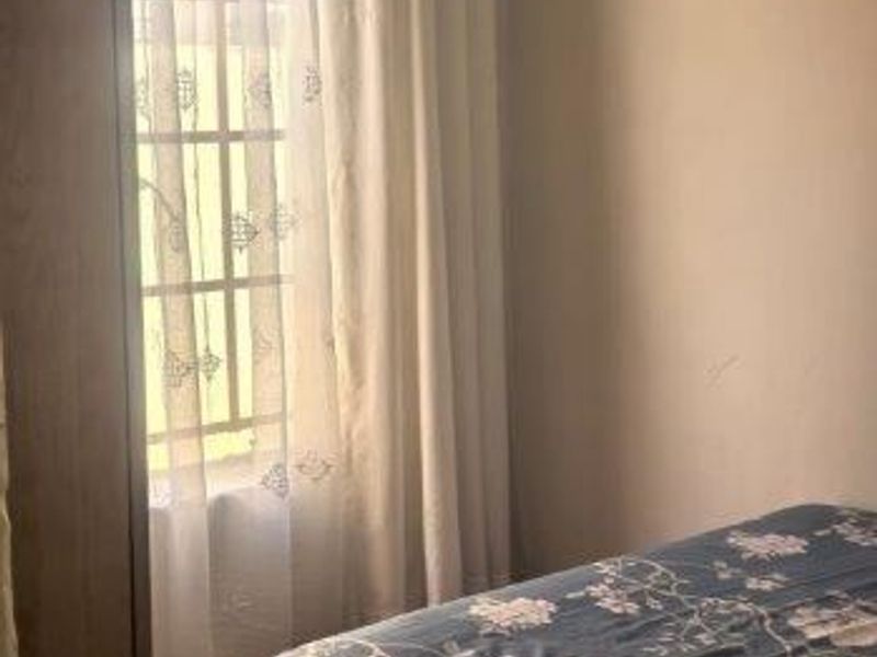 A bedroom featuring tiled flooring and a window with curtain rod, offering a simple and functional living space.