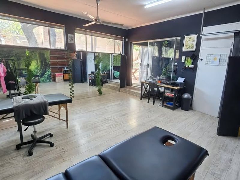 A spacious, light-filled utility room featuring large windows, sliding glass doors leading to the exterior, and durable tiled flooring.