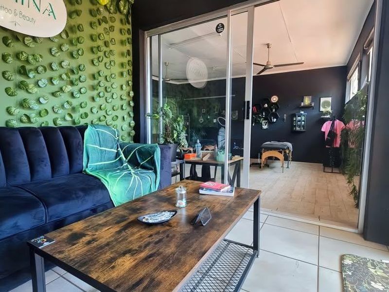 Open plan commercial space featuring sliding glass doors, ceiling fans, and a combination of tiled and wood-look laminate flooring.