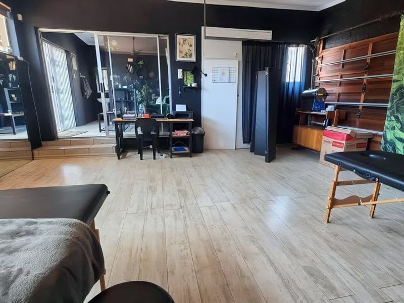 A versatile utility space featuring wood-look tile flooring, wall-mounted shelving tracks, and a sliding glass door providing access to an adjacent area.