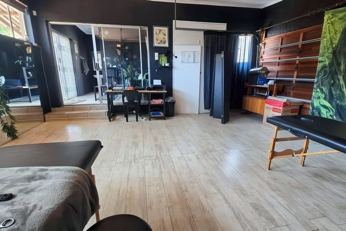 A versatile utility space featuring wood-look tile flooring, wall-mounted shelving tracks, and a sliding glass door providing access to an adjacent area.