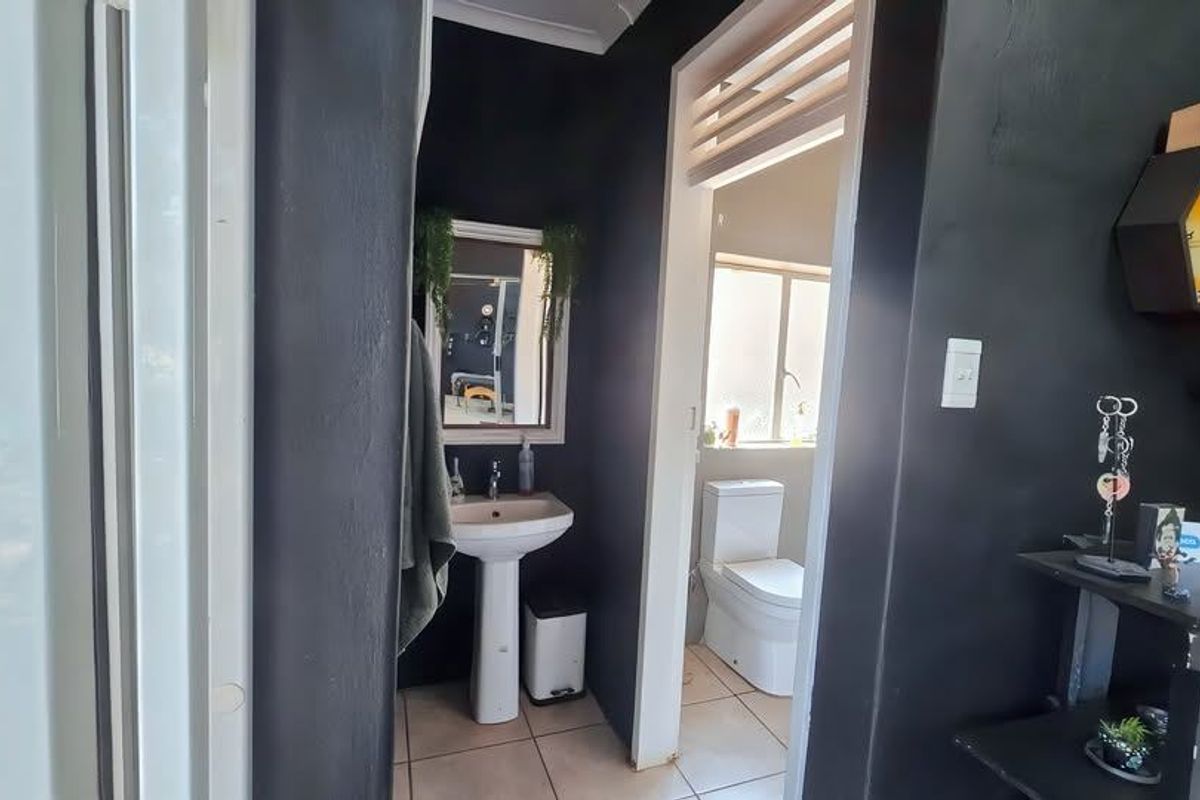A compact bathroom featuring a pedestal washbasin and a separate toilet area with tiled flooring and dark painted walls.