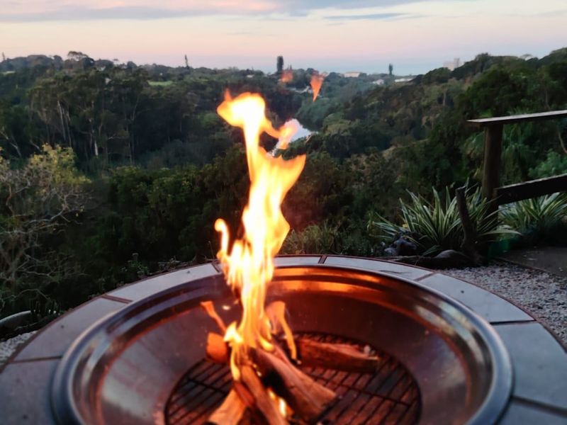 Outdoor patio area featuring a built-in fire pit and timber railing, overlooking a scenic natural landscape.