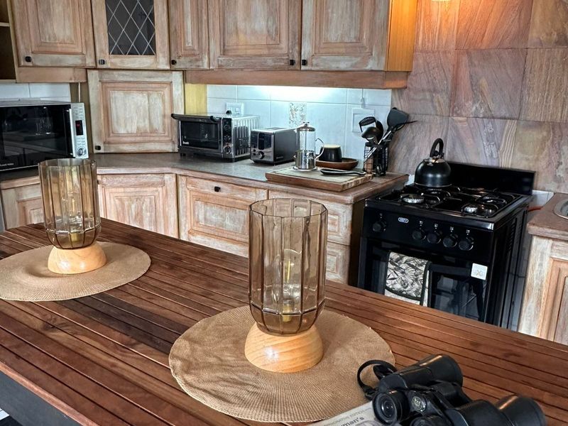 A rustic-style kitchen featuring wooden cabinetry, stone tile backsplash, and a gas stove, offering a warm and traditional aesthetic.
