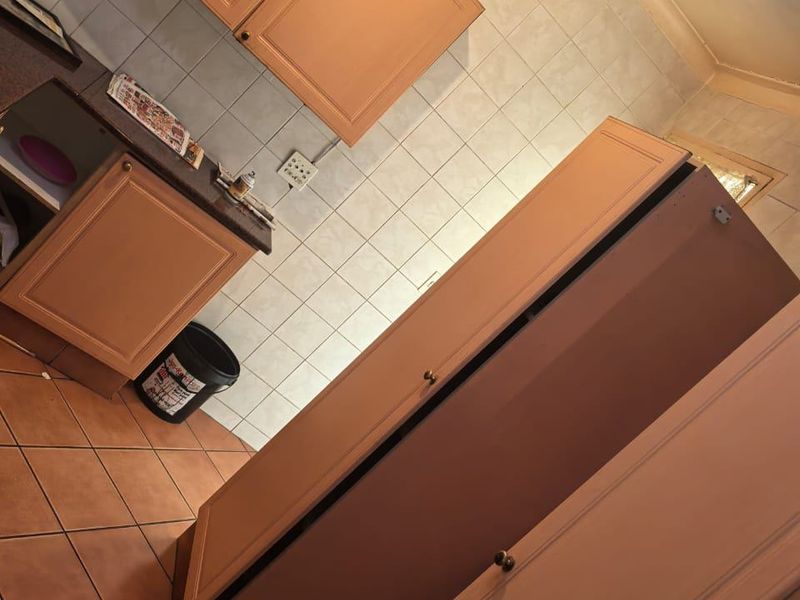 A dated kitchen featuring tiled flooring, a tiled backsplash, and built-in cabinetry with track lighting.