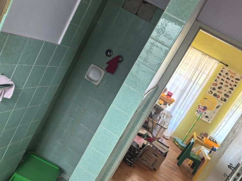 A dated bathroom featuring green ceramic wall tiles and a shower enclosure, requiring maintenance and cosmetic updates to improve its overall condition.