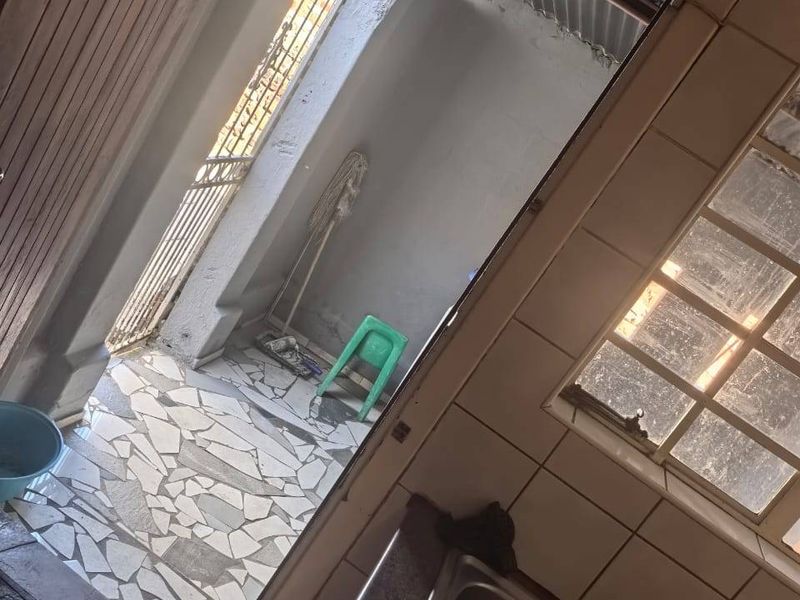 A functional scullery or utility area featuring a stainless steel sink, tiled splashback, and direct access to an outdoor paved courtyard.