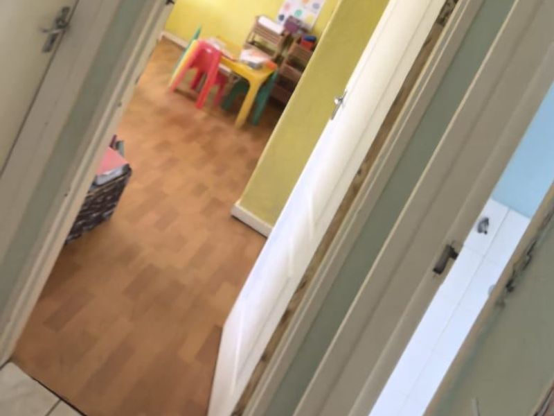 A view through a doorway into a room with yellow walls and laminate flooring, currently utilized as a child's play or learning space.