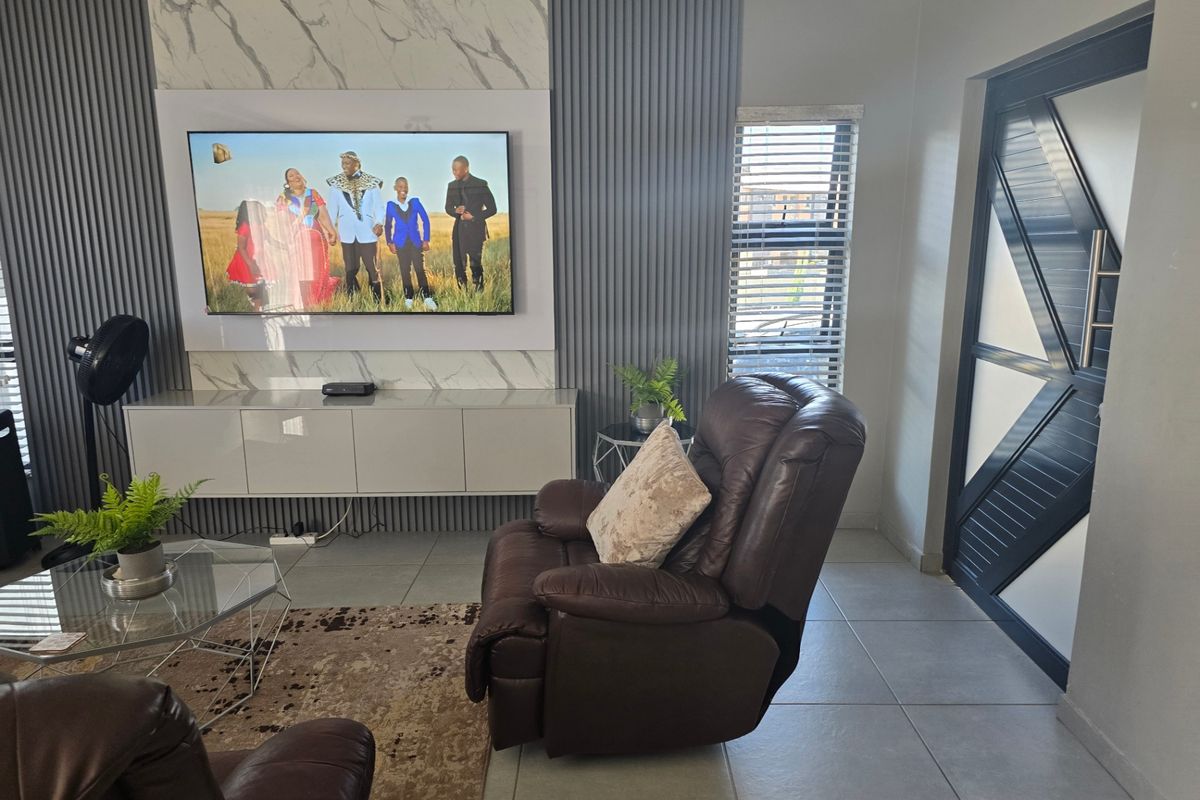 Modern living room featuring a stylish marble-look feature wall with vertical slat paneling, built-in media console, and neutral tiled flooring.