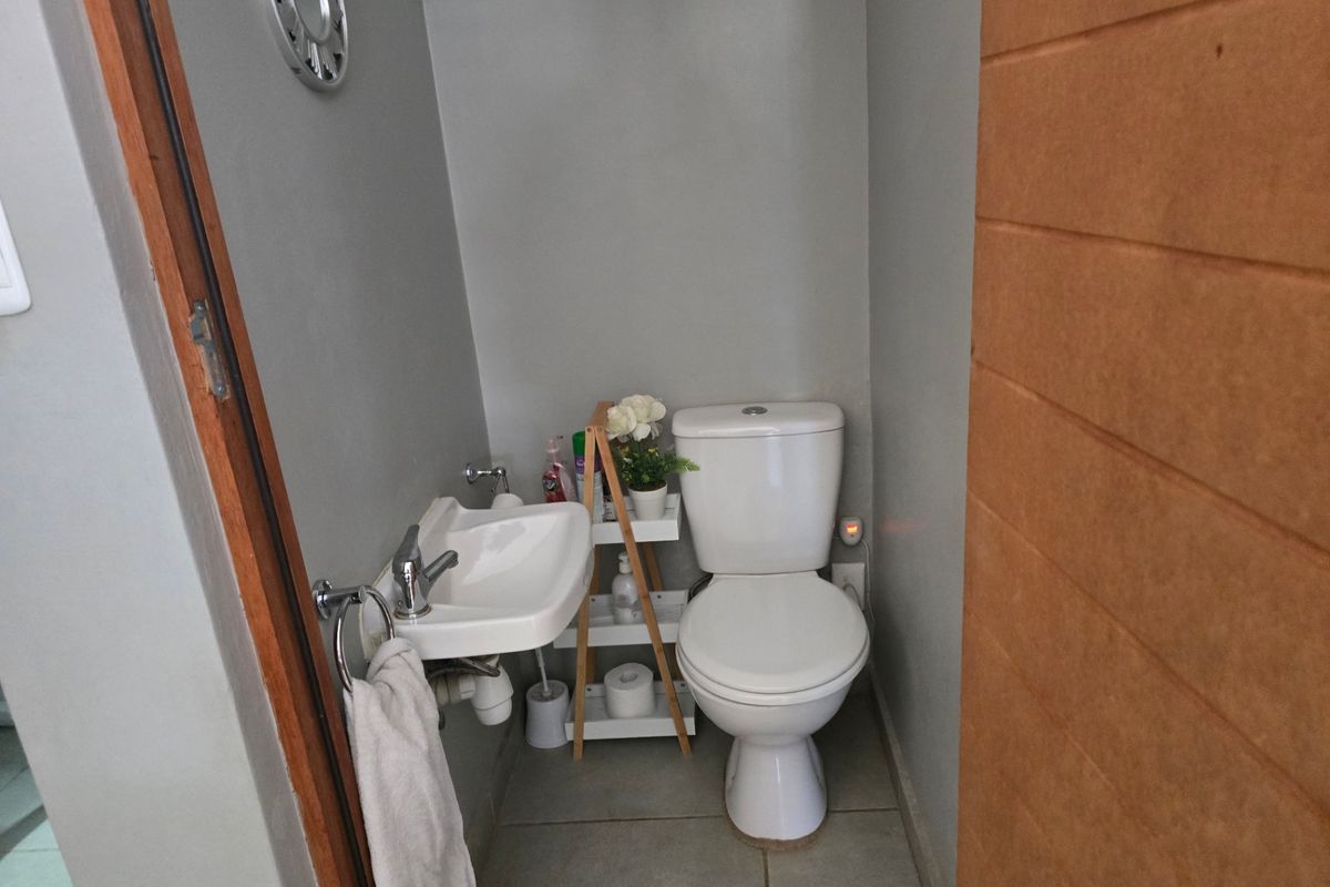 A compact guest bathroom featuring a white toilet and a wall-mounted basin with modern fixtures.