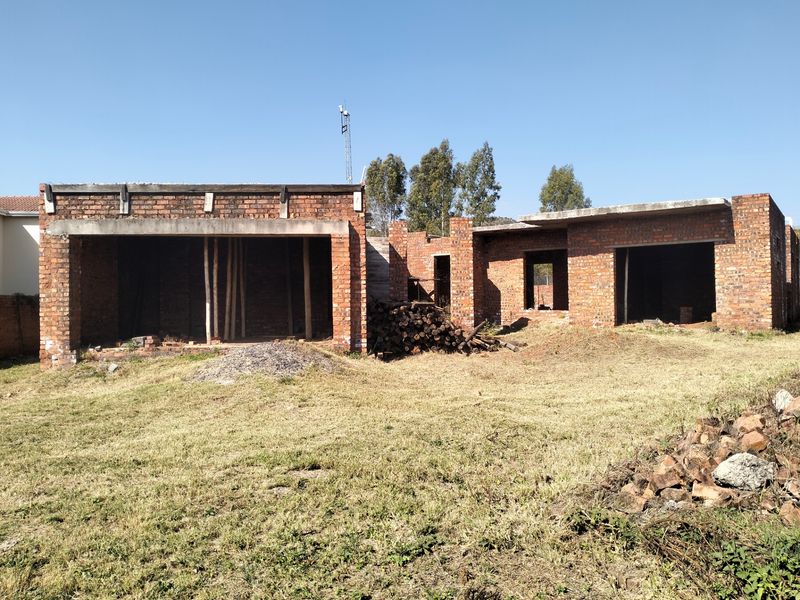 An unfinished residential property structure showing exposed brickwork and concrete slabs, currently in the early stages of construction.