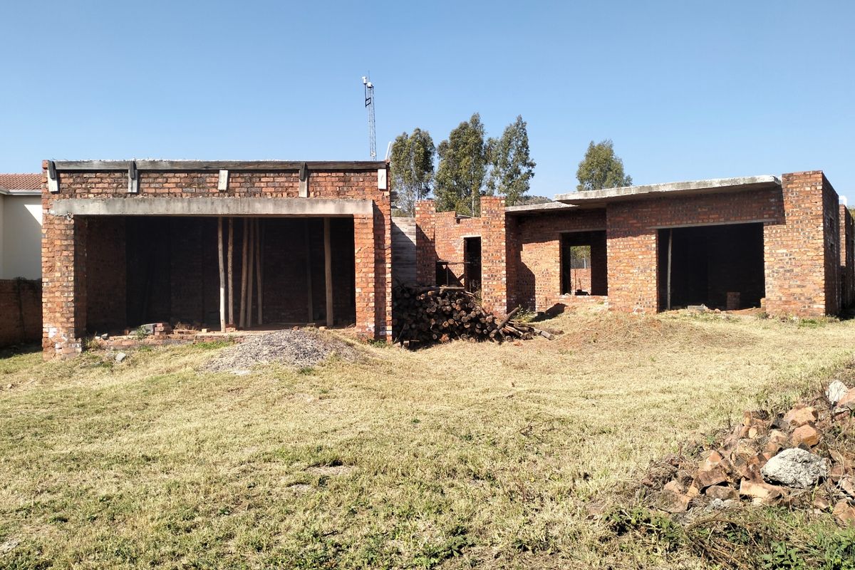 An unfinished residential property structure showing exposed brickwork and concrete slabs, currently in the early stages of construction.