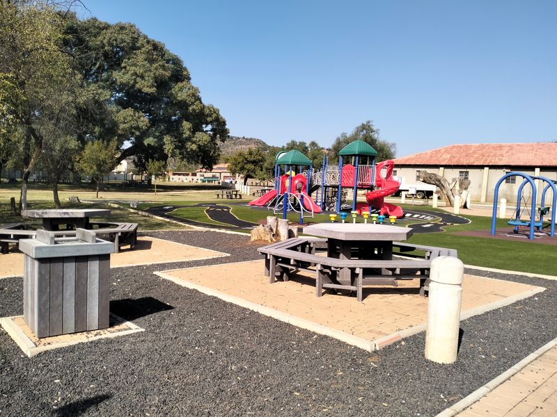 A well-maintained communal garden area featuring a playground, paved seating areas, and established landscaping.
