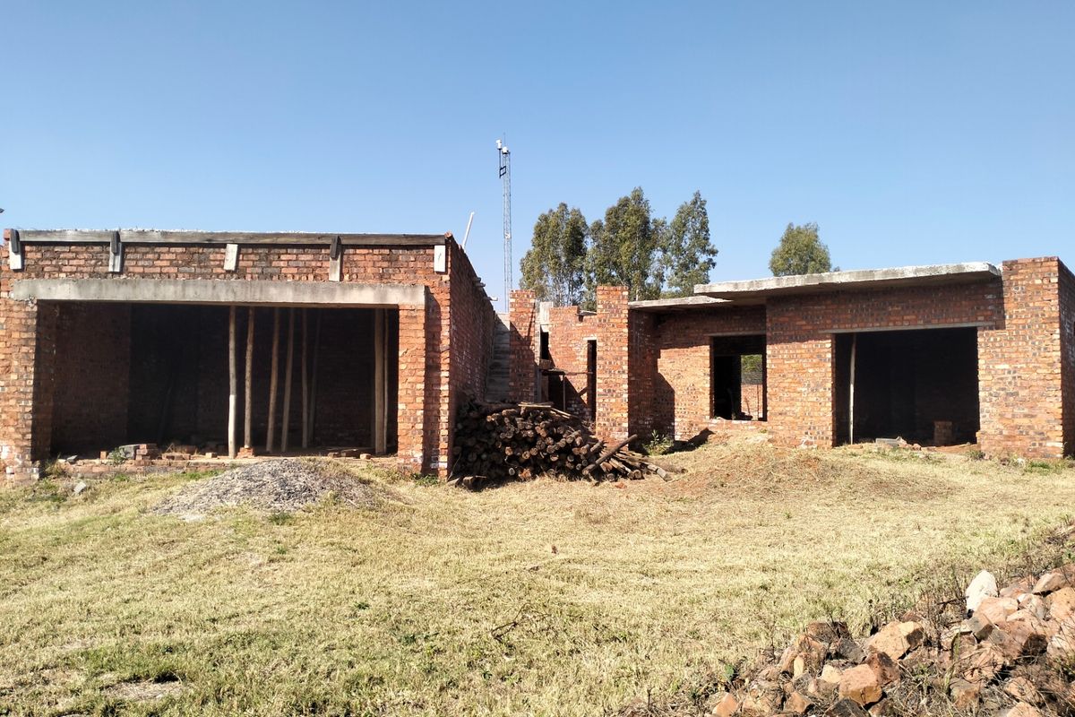 A rear view of a residential property currently under construction, featuring exposed brickwork and concrete structural elements in an unfinished state.