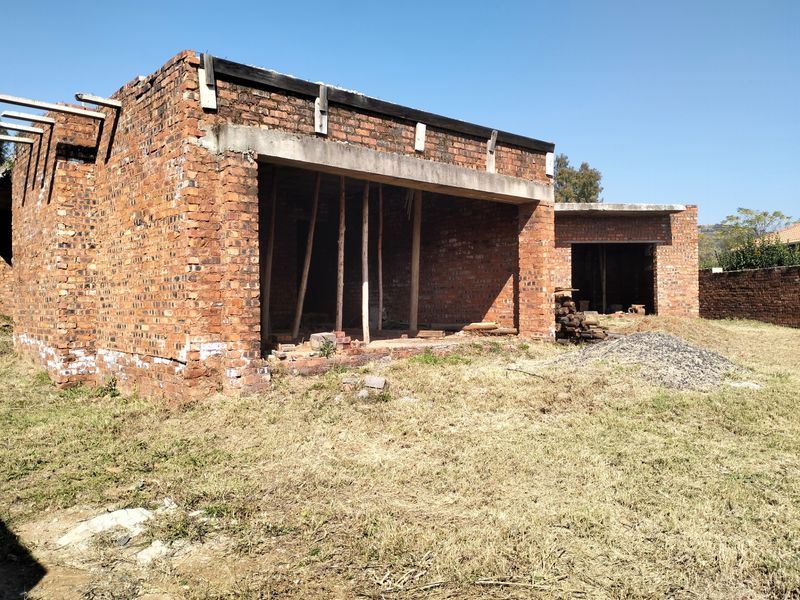 An unfinished brick structure showing the exterior shell of a property under construction, featuring exposed masonry and concrete lintels.