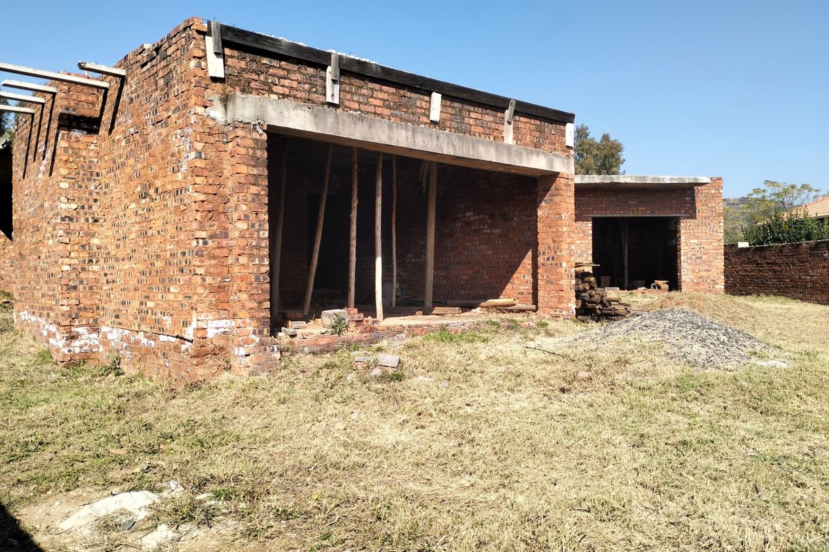 An unfinished brick structure showing the exterior shell of a property under construction, featuring exposed masonry and concrete lintels.