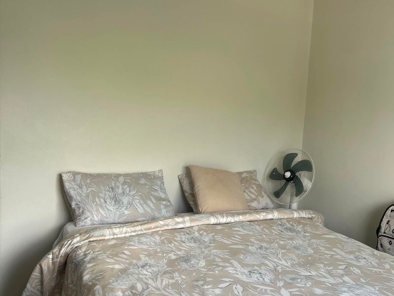 A simple bedroom featuring neutral wall paint, tiled flooring, and a central pendant light fixture.