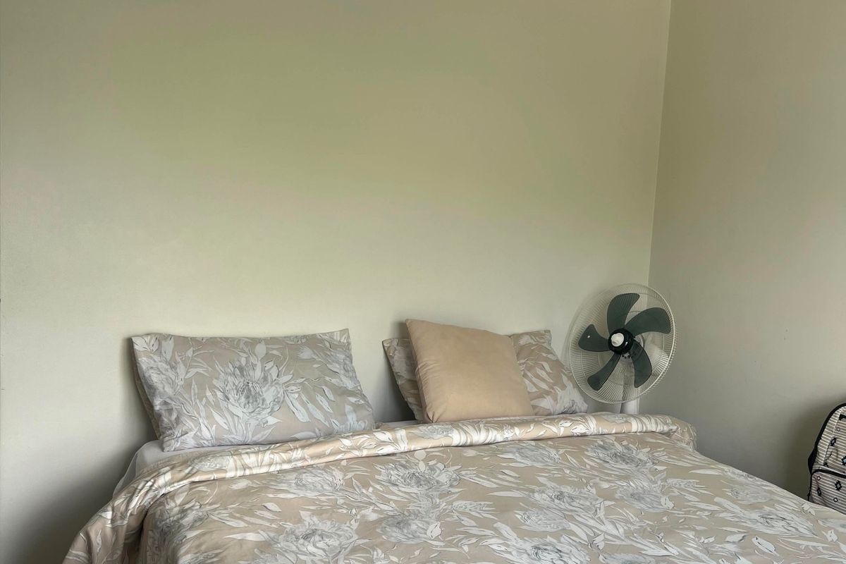 A simple bedroom featuring neutral wall paint, tiled flooring, and a central pendant light fixture.