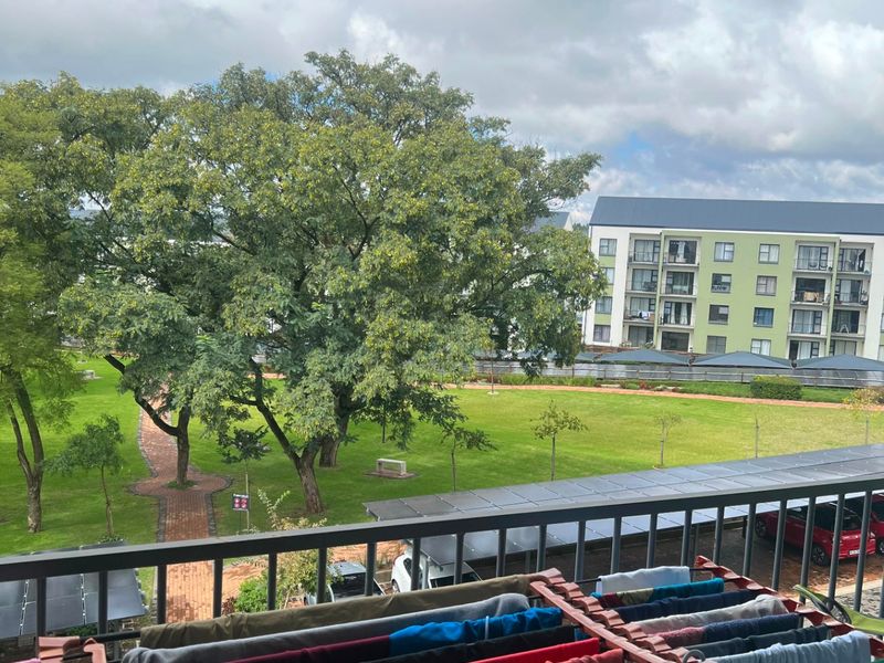 A balcony view overlooking a communal garden area and neighbouring apartment buildings.