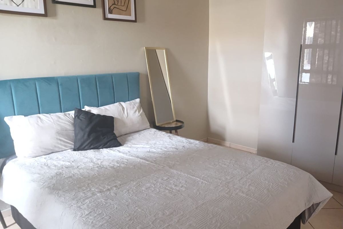 A well-maintained bedroom featuring neutral walls, tiled flooring, and a modern built-in wardrobe.
