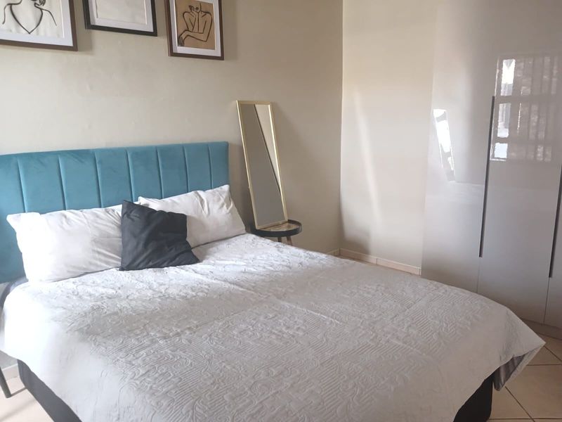 A well-maintained bedroom featuring neutral walls, tiled flooring, and a modern built-in wardrobe.