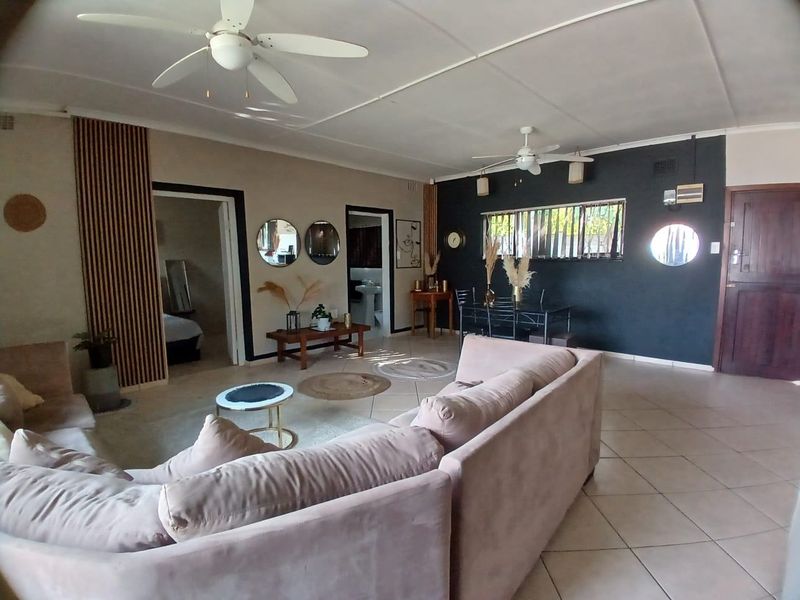 Spacious open-plan living and dining area featuring tiled flooring, ceiling fans, and decorative timber wall paneling.