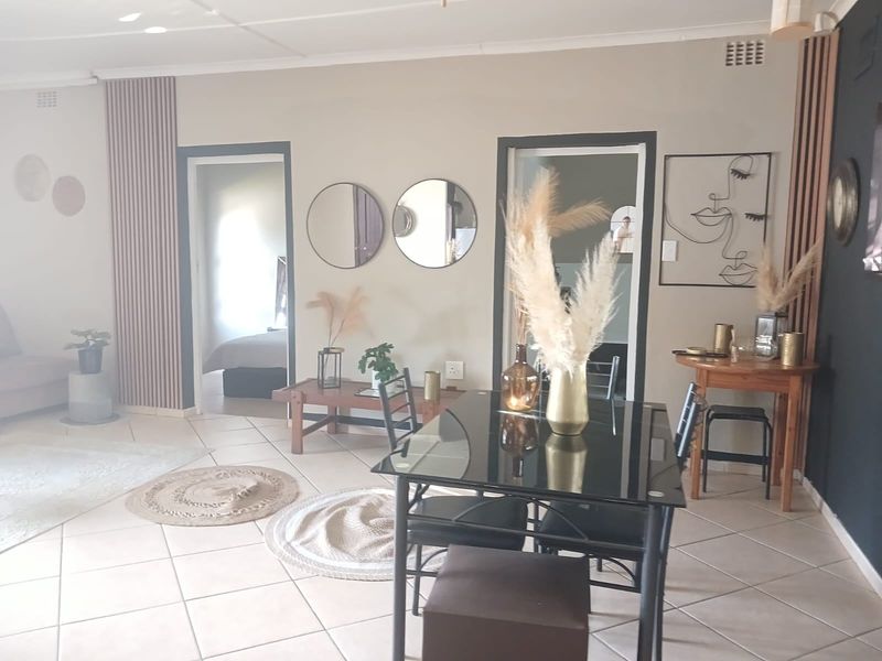 A well-maintained living area featuring neutral wall tones, decorative vertical wall paneling, and tiled flooring, providing a bright and inviting atmosphere.