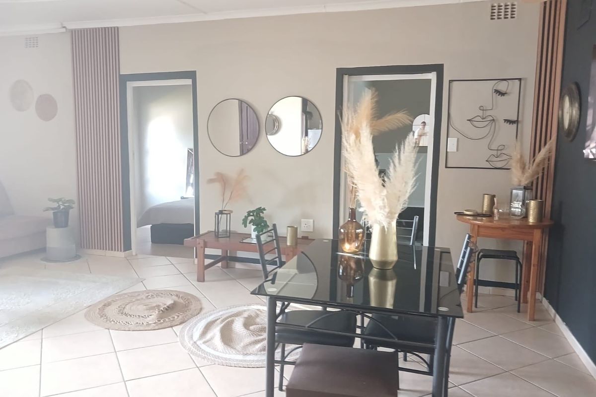 A well-maintained living area featuring neutral wall tones, decorative vertical wall paneling, and tiled flooring, providing a bright and inviting atmosphere.