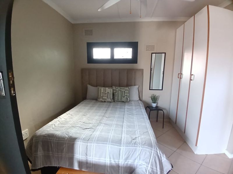 A functional bedroom featuring tiled flooring, a built-in wardrobe, and a ceiling fan, providing a comfortable and practical living space.