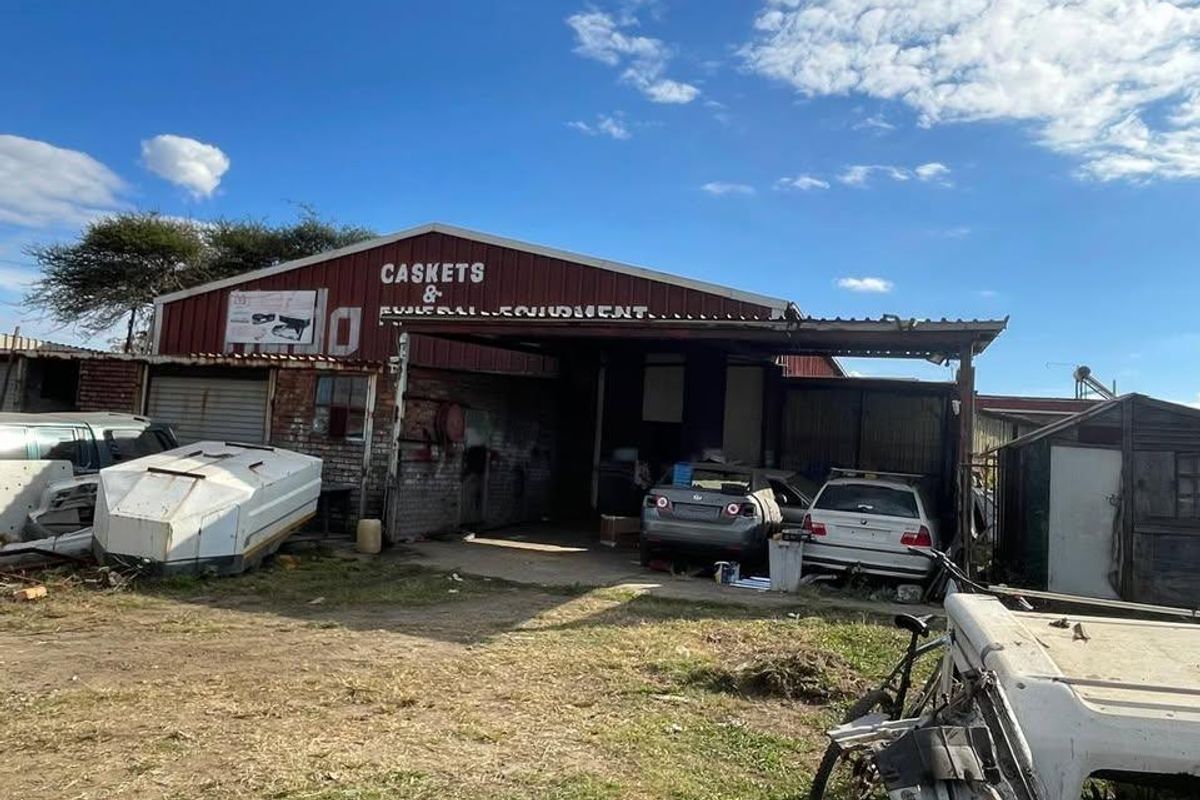 Industrial warehouse facility featuring corrugated metal cladding and a covered loading area, currently showing significant signs of wear and exterior deterioration.