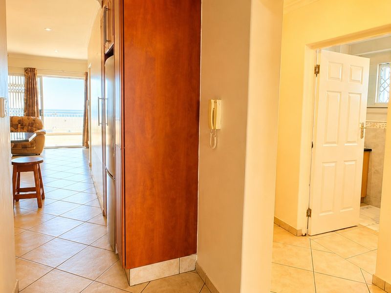 A tiled hallway connecting the kitchen area to the living space and bathroom, featuring built-in cabinetry and an intercom system.