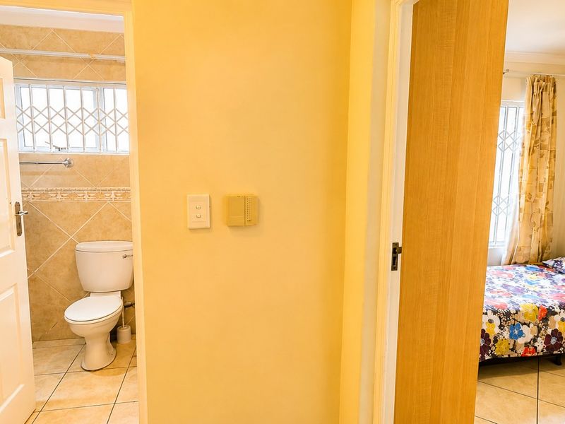 A view from a hallway looking into a bathroom and a bedroom, featuring tiled flooring and standard interior finishes.