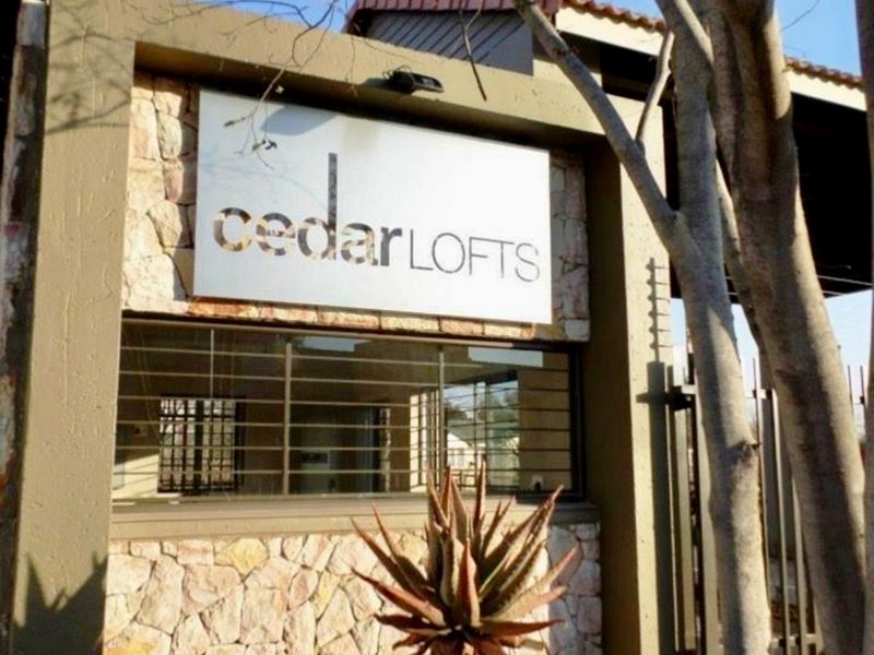 Entrance facade of Cedar Lofts apartment complex featuring stone cladding, security gate, and building signage.
