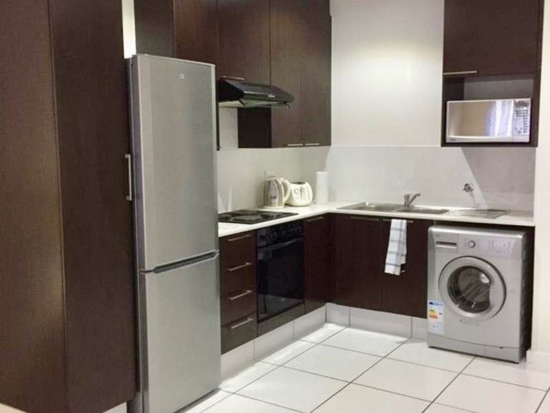 Modern kitchen featuring dark wood cabinetry, integrated appliances, tiled flooring, and recessed lighting, providing a functional and clean cooking space.
