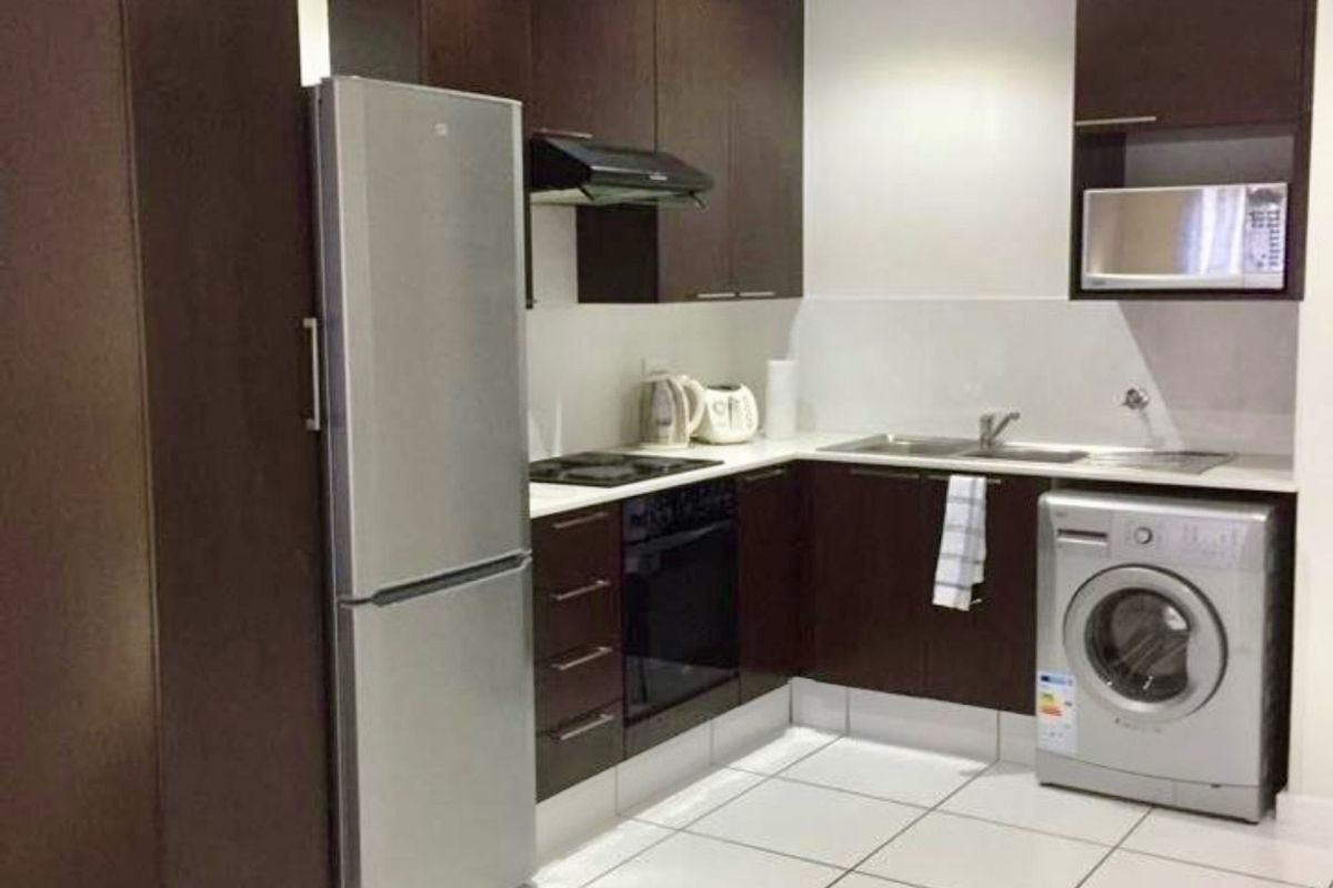 Modern kitchen featuring dark wood cabinetry, integrated appliances, tiled flooring, and recessed lighting, providing a functional and clean cooking space.