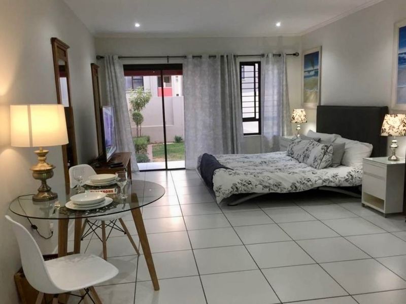 A spacious bedroom featuring tiled flooring, recessed lighting, and a sliding glass door providing direct access to an outdoor area.