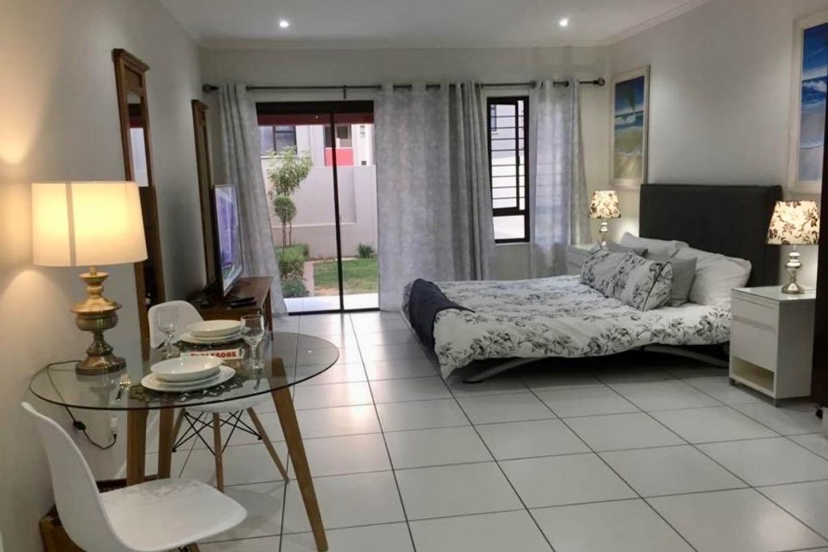 A spacious bedroom featuring tiled flooring, recessed lighting, and a sliding glass door providing direct access to an outdoor area.