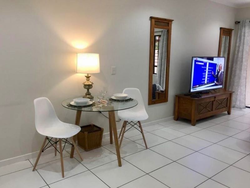 A bright living area featuring neutral tiled flooring and clean wall finishes, providing a versatile space for relaxation and dining.