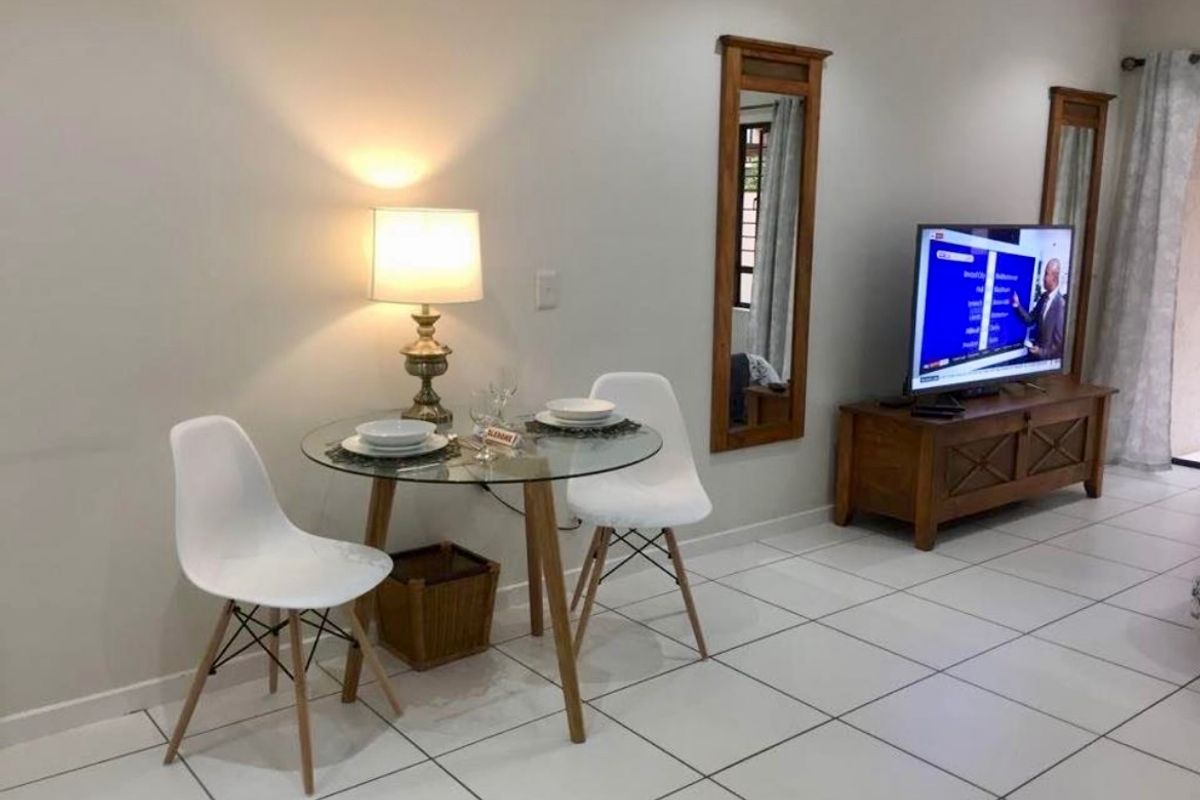 A bright living area featuring neutral tiled flooring and clean wall finishes, providing a versatile space for relaxation and dining.