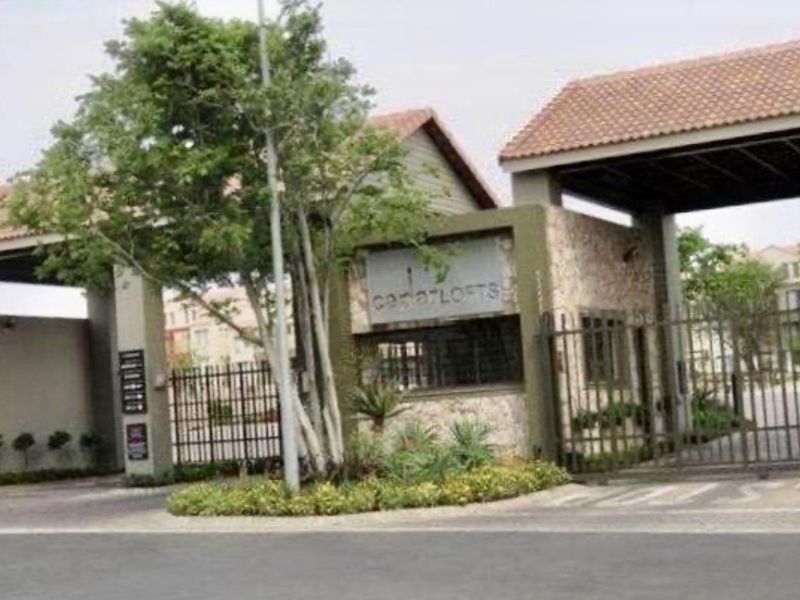 The main entrance and security gatehouse of the Cedar Lofts apartment complex, featuring stone cladding and a secure gated access point.