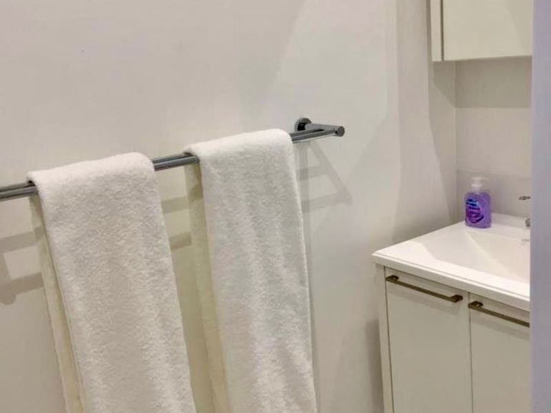 A compact bathroom featuring a white vanity cabinet with an integrated sink, a mirrored medicine cabinet, and a wall-mounted towel rail.