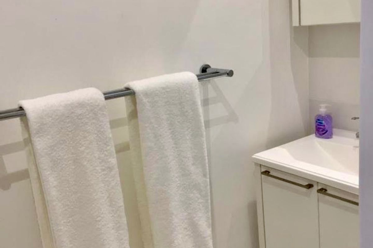 A compact bathroom featuring a white vanity cabinet with an integrated sink, a mirrored medicine cabinet, and a wall-mounted towel rail.