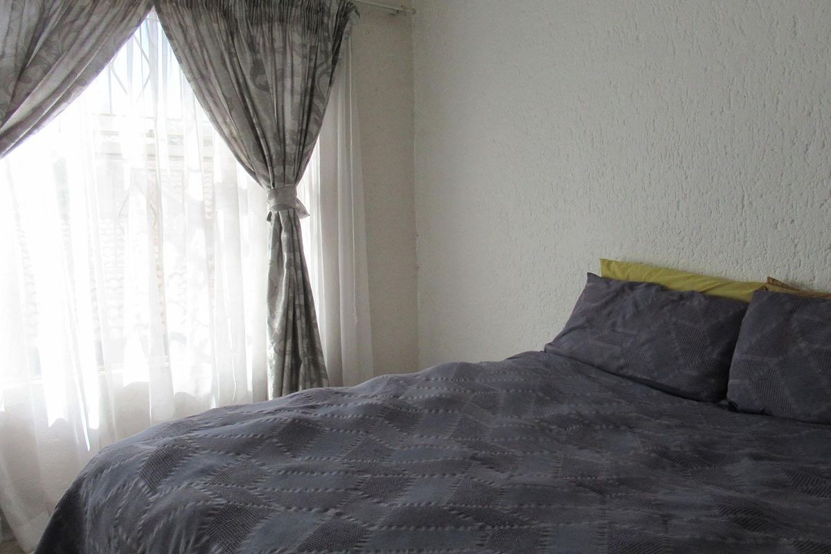 A bedroom featuring textured wall finishes and a window with installed curtain rods.