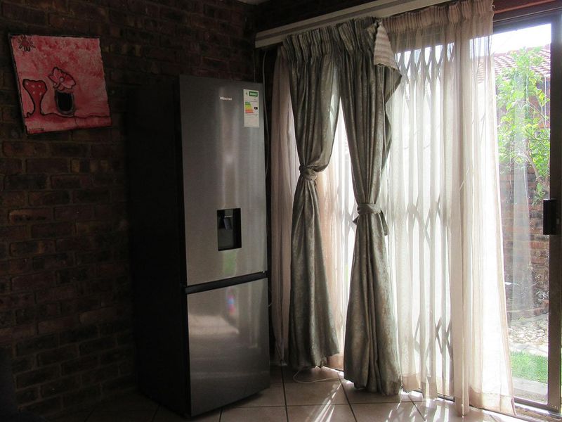 Living area featuring an exposed brick wall and a sliding glass door with security gate, providing direct access to the rear garden.