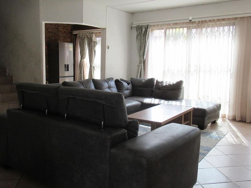 Spacious living area featuring tiled flooring and large sliding glass doors that provide access to the exterior, with an adjacent staircase.