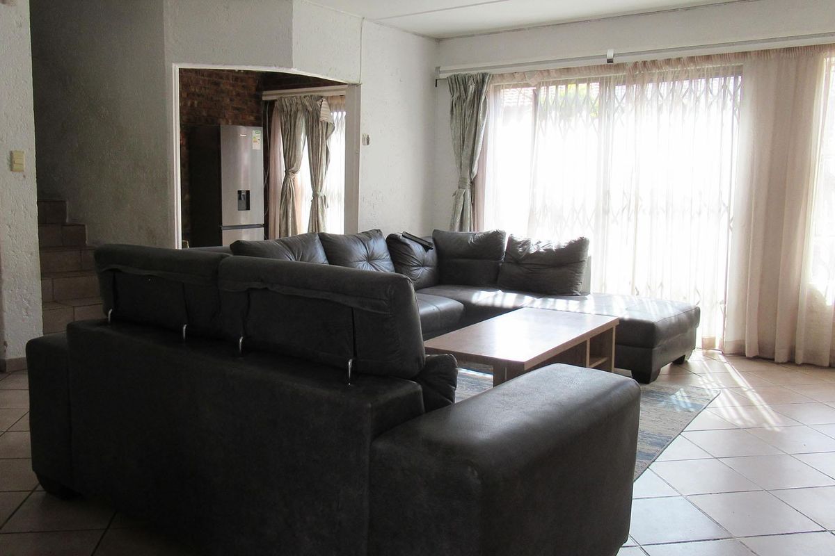 Spacious living area featuring tiled flooring and large sliding glass doors that provide access to the exterior, with an adjacent staircase.