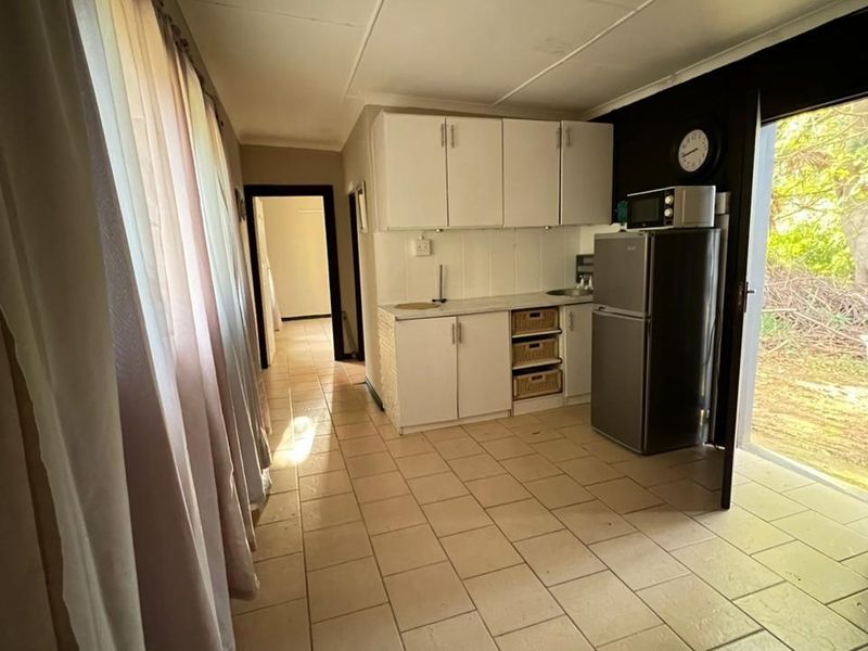 A functional kitchen area featuring built-in cabinetry, tiled flooring, and direct access to the exterior, offering a practical layout for daily use.