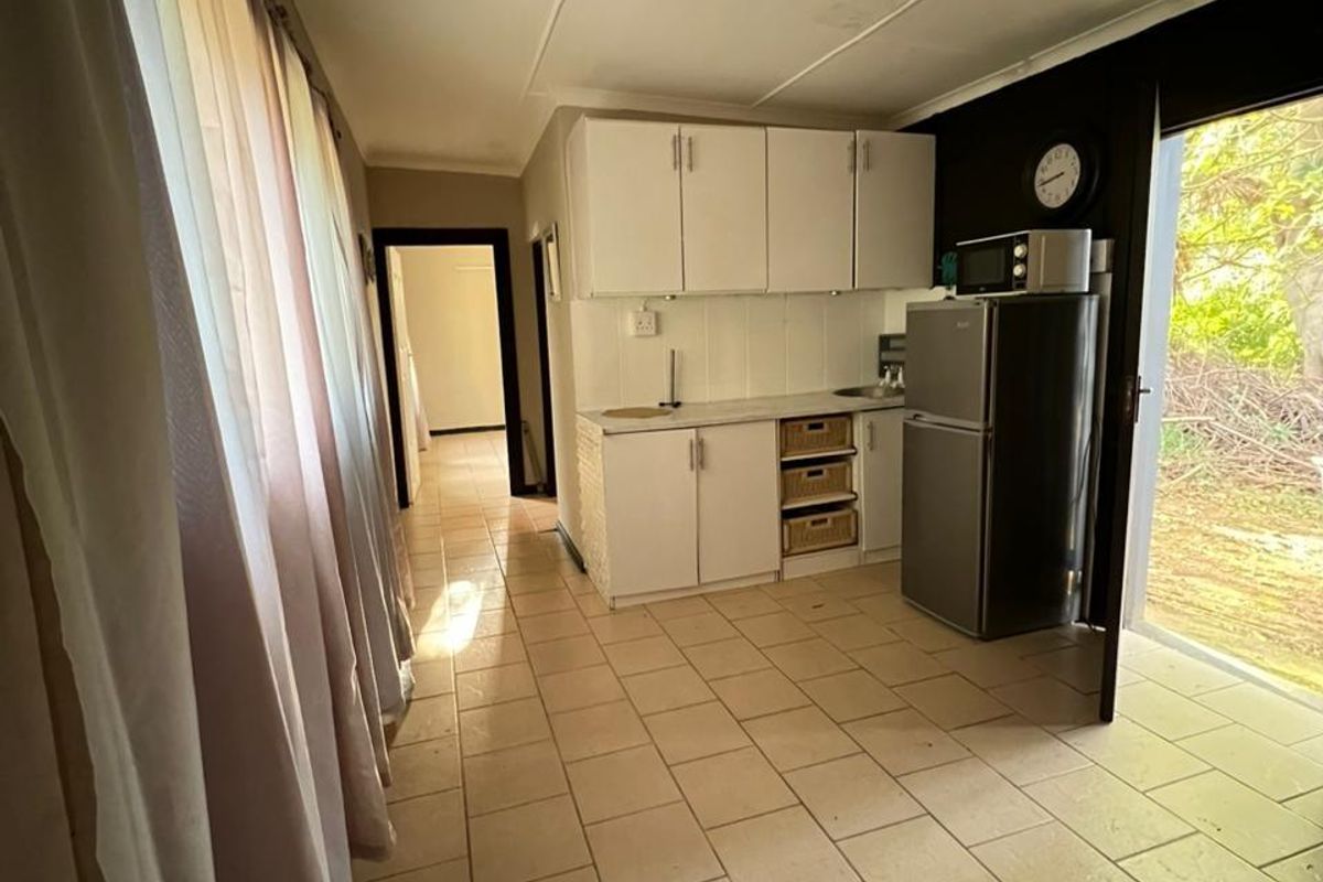 A functional kitchen area featuring built-in cabinetry, tiled flooring, and direct access to the exterior, offering a practical layout for daily use.
