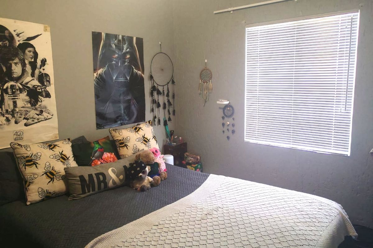 A bedroom featuring neutral wall paint and a window fitted with venetian blinds.